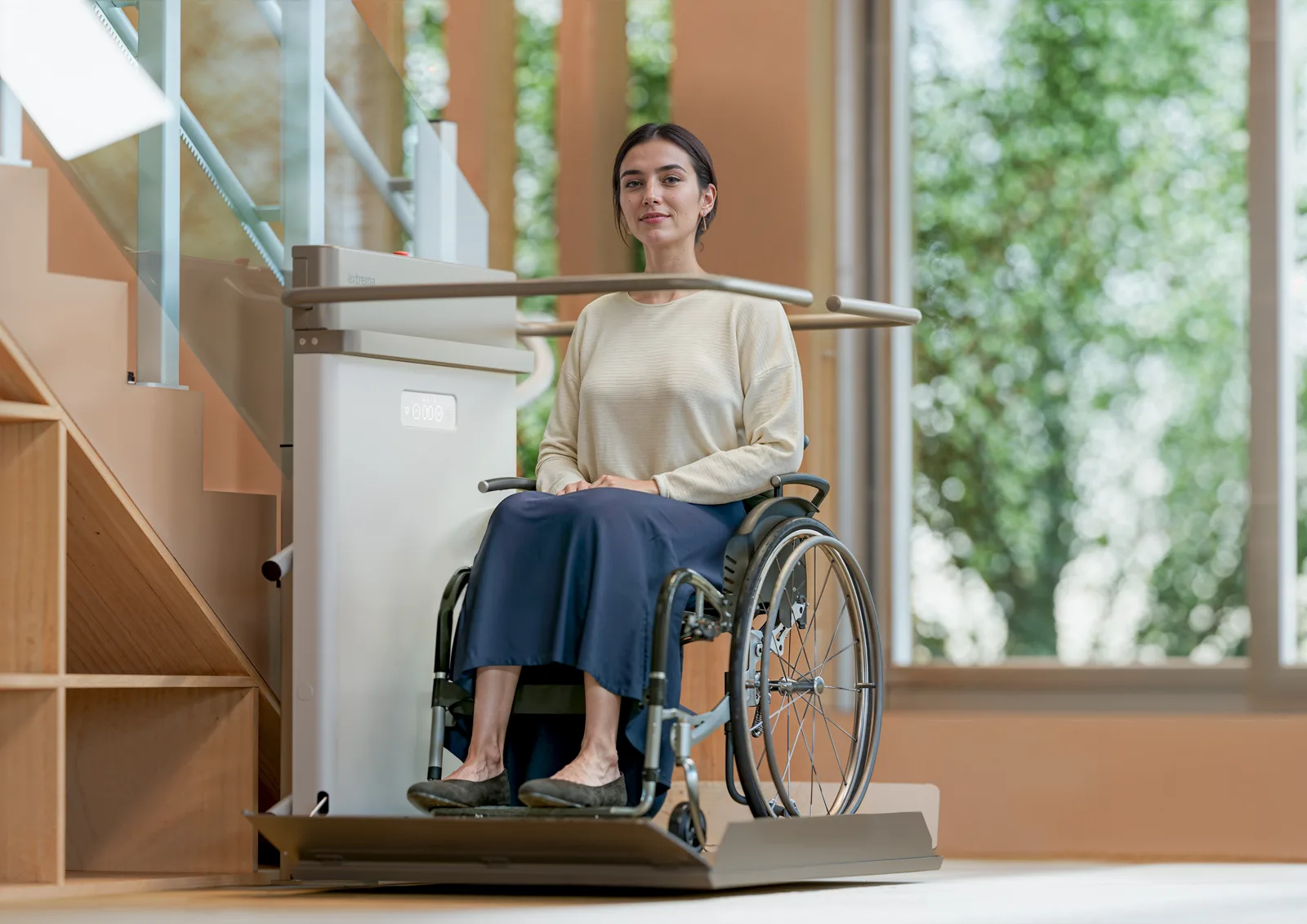 Rollstuhlfahrerin fährt mit dem Plattformlift Slim S2 die Treppe hinauf