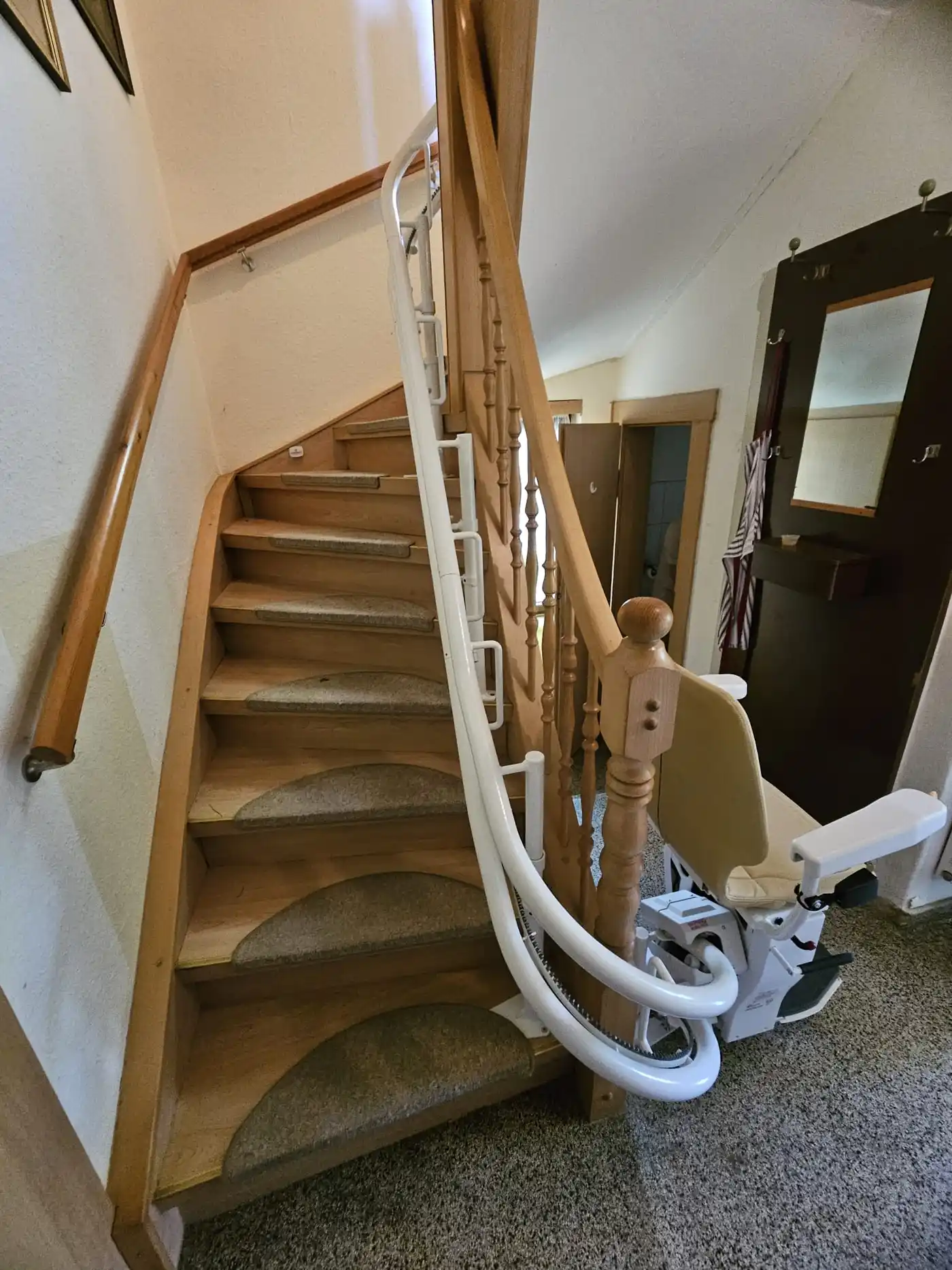 Kurvenlift-Referenz: Treppenlift an gewendelter Holztreppe, Schiene eng am Geländer geführt